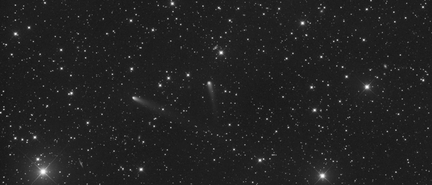 Ein schwarz-weißes astronomisches Bild zeigt einen sternenübersäten Nachthimmel. Zwei Kometen mit langen, diffusen Schweifen sind in der Bildmitte sichtbar. Die Sterne variieren in Helligkeit und sind gleichmäßig über das Bild verteilt. Der Hintergrund ist dunkel, was die Leuchtkraft der Himmelskörper hervorhebt. Ein schwarz-weißes astronomisches Bild zeigt einen sternenübersäten Nachthimmel. Zwei Kometen mit langen, diffusen Schweifen sind in der Bildmitte sichtbar. Die Sterne variieren in Helligkeit und sind gleichmäßig über das Bild verteilt. Der Hintergrund ist dunkel, was die Leuchtkraft der Himmelskörper hervorhebt.
