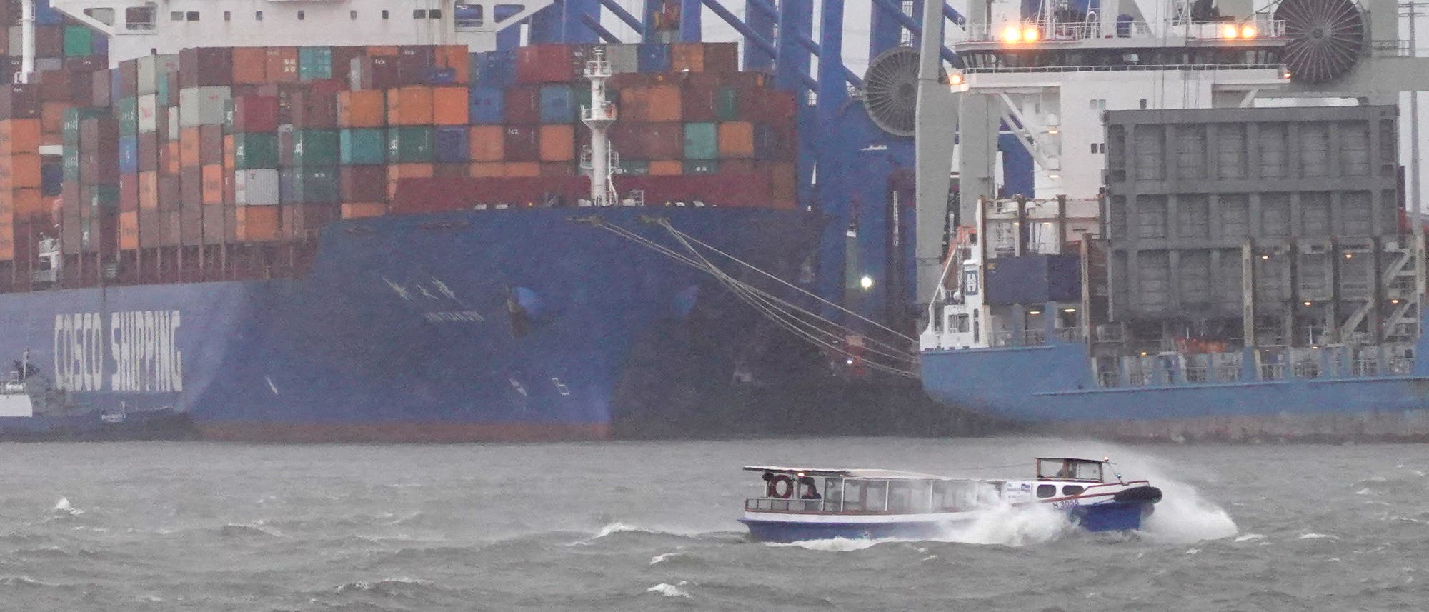 Barkasse im Hamburger Hafen bei Sturm, im Hintergrund Containerschiffe.
