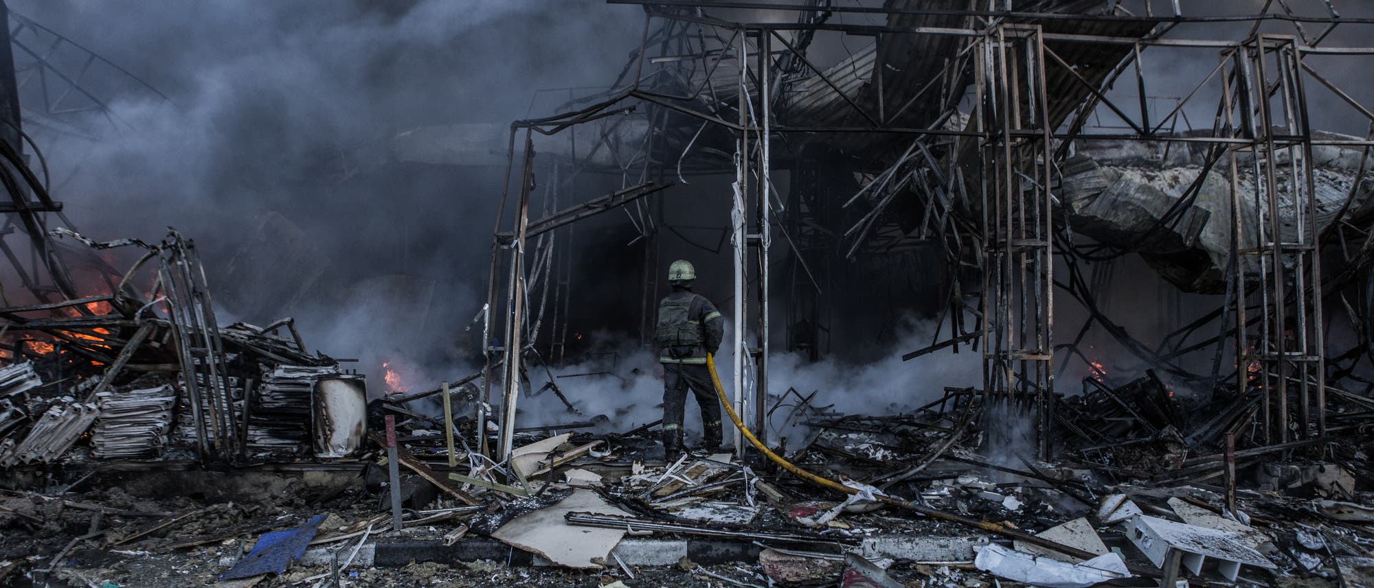 Ein Feuerwehrmann versucht, ein zerbombtes Gebäude in Charkiw zu löschen. Aufnahme vom 16. März 2022.