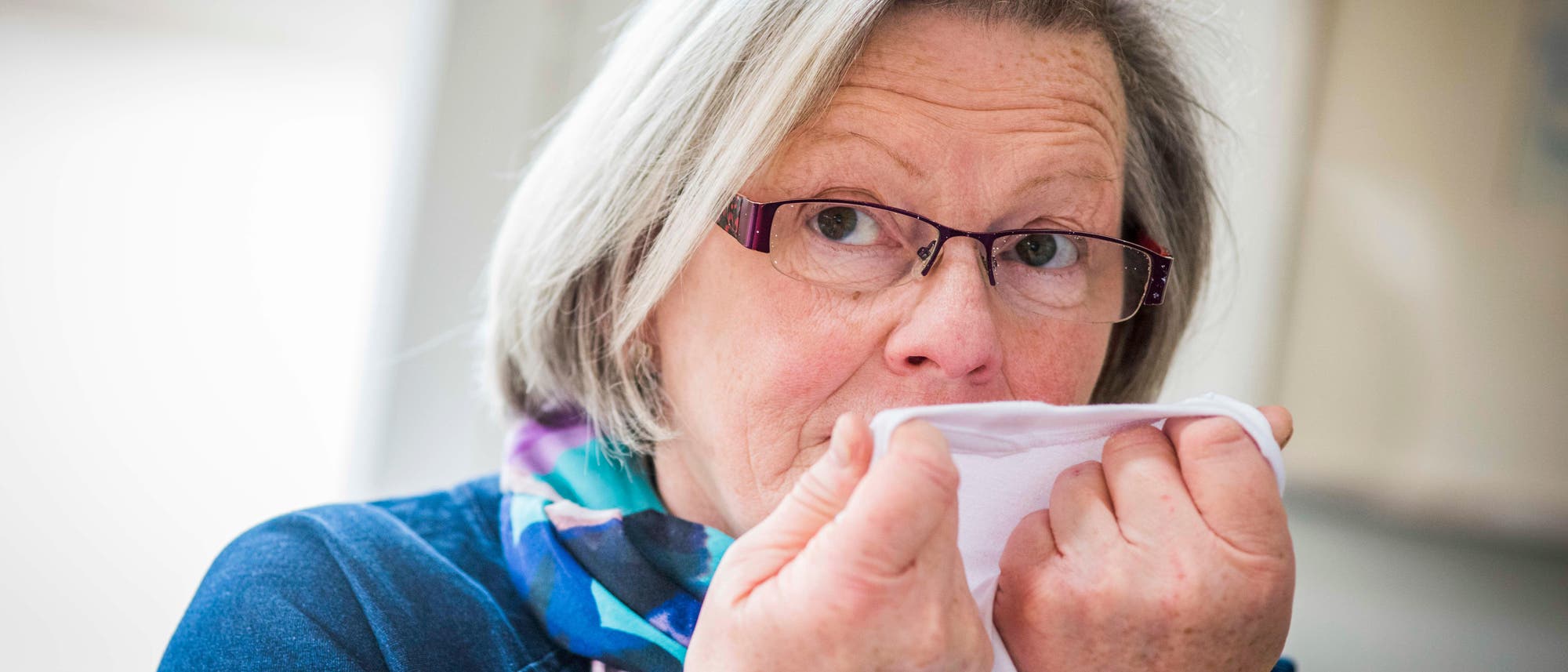 Die pensionierte Krankenschwester Joy Milne riecht an einem Stück Kleidung.