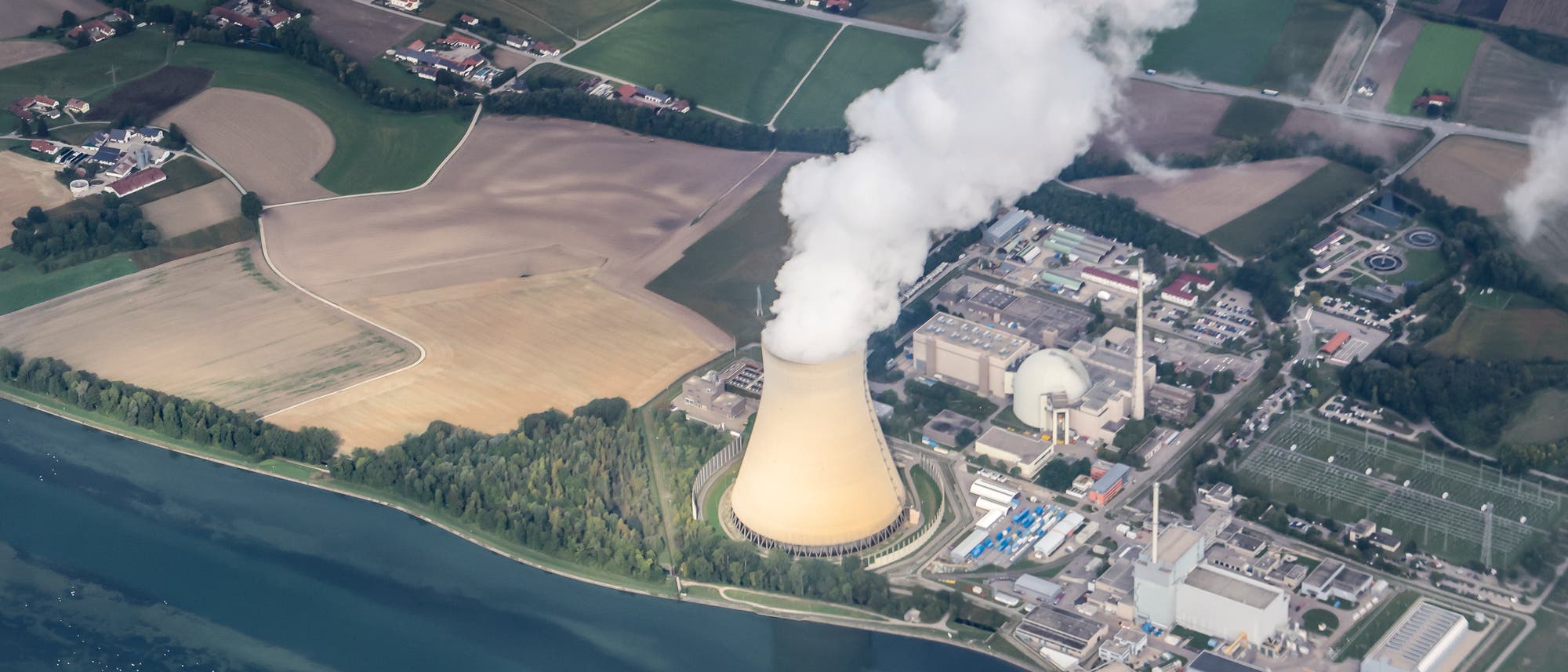 Luftaufnahme des Kernkraftwerks Isar-2. Aus dem Kühlturm quillt Dampf. 