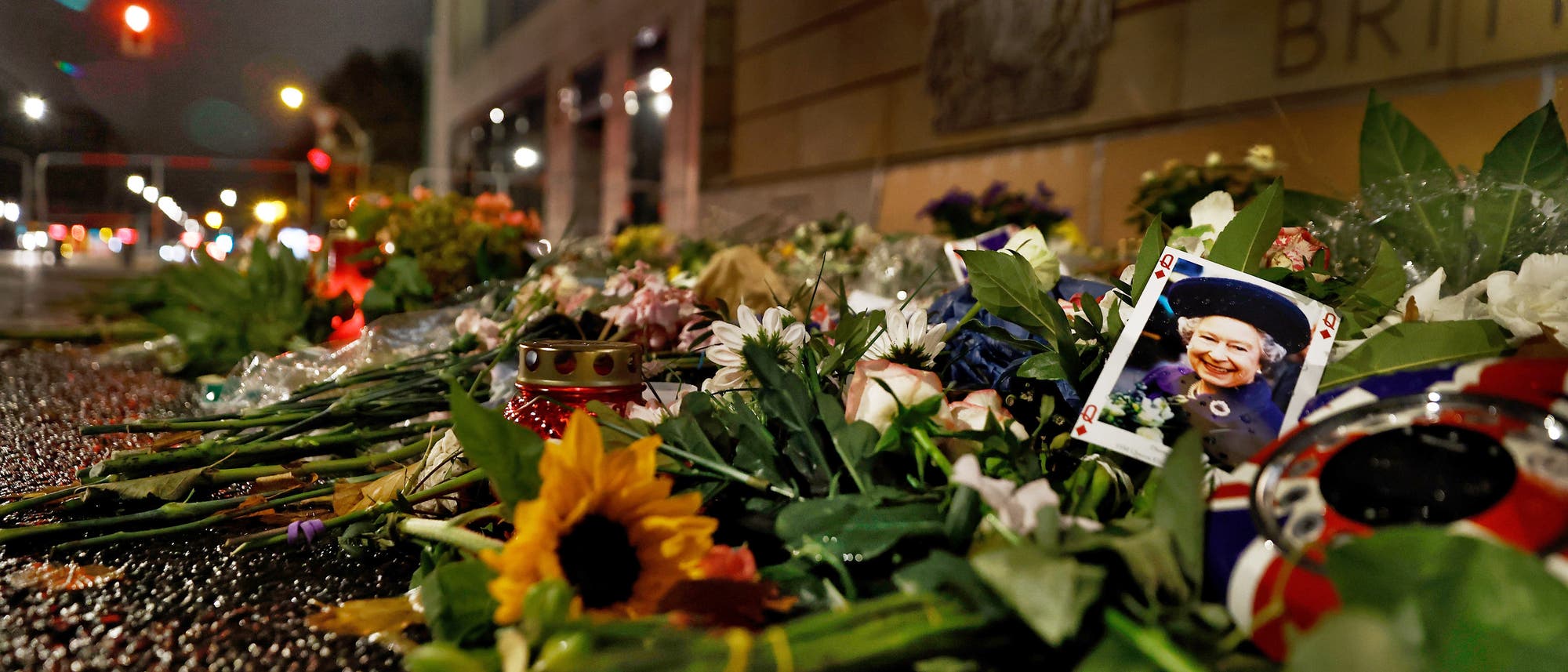 Blumen und ein Foto von Elisabeth II. vor der britischen Botschaft