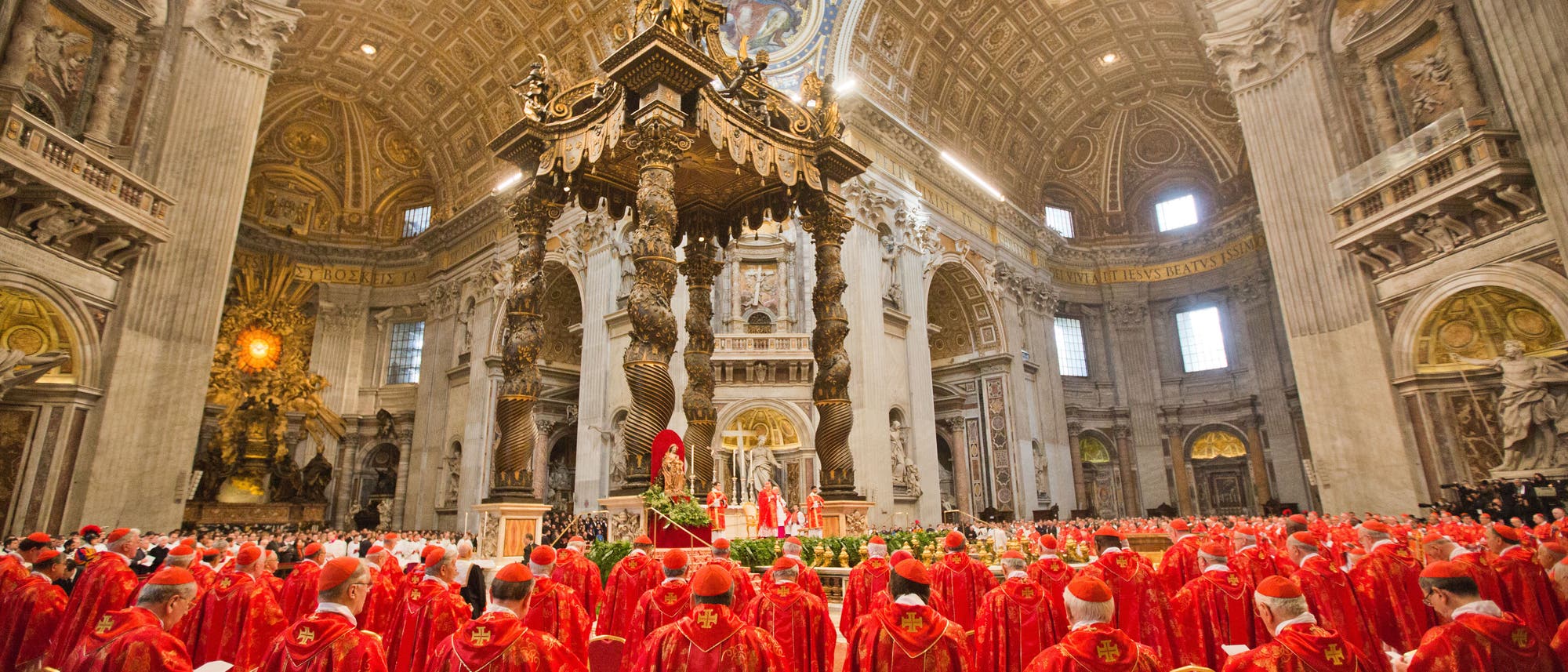 Eine große Versammlung von Kardinälen in roten Gewändern steht in der prunkvollen St. Petersbasilika im Vatikan. Der Innenraum ist reich verziert mit kunstvollen Säulen und einem beeindruckenden Baldachin über dem Altar. Die Kuppel ist mit kunstvollen Fresken geschmückt. Die Kardinäle sind nach vorne zum Altar ausgerichtet, wo eine religiöse Zeremonie stattfindet. Eine große Versammlung von Kardinälen in roten Gewändern steht in der prunkvollen St. Petersbasilika im Vatikan. Der Innenraum ist reich verziert mit kunstvollen Säulen und einem beeindruckenden Baldachin über dem Altar. Die Kuppel ist mit kunstvollen Fresken geschmückt. Die Kardinäle sind nach vorne zum Altar ausgerichtet, wo eine religiöse Zeremonie stattfindet.