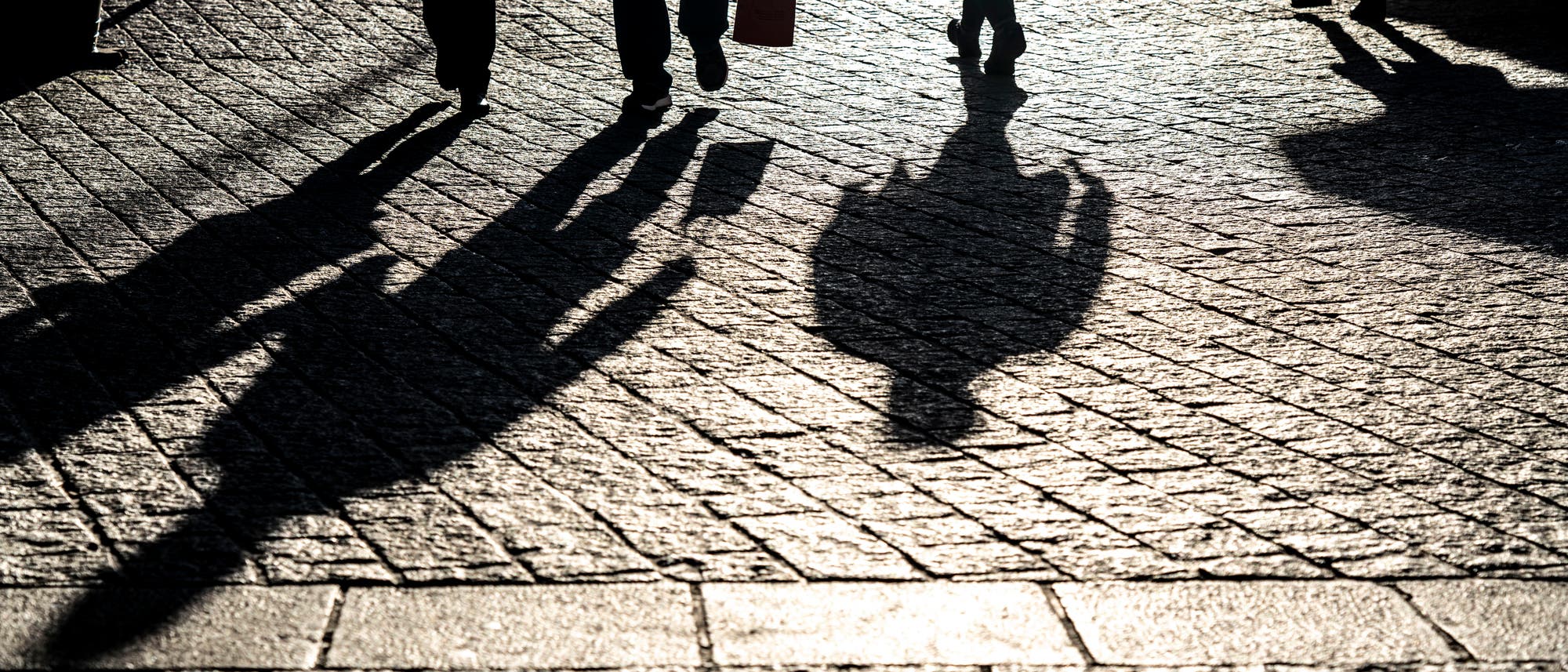 Die Schatten von drei Fußgängern in Dortmund. 