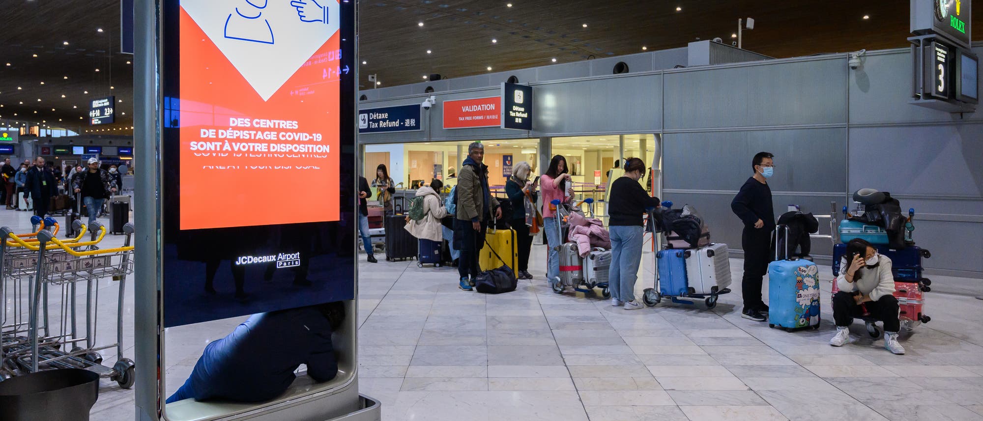 Reisende aus China stehen in einer Schlange am Pariser Flughafen Charles-de-Gaulle