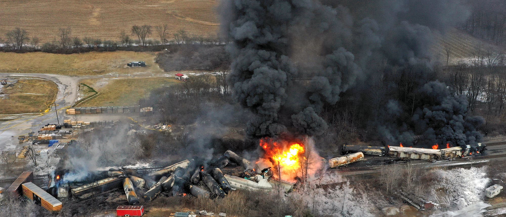 Eine Luftbildaufnahme zeigt die Ausmaße des Zugunglücks: Die Waggons des Güterzugs sind entgleist und haben sich ineinandergeschoben. Einige Waggons stehen in Flammen und es sind schwarze Rauchwolken zu sehen.