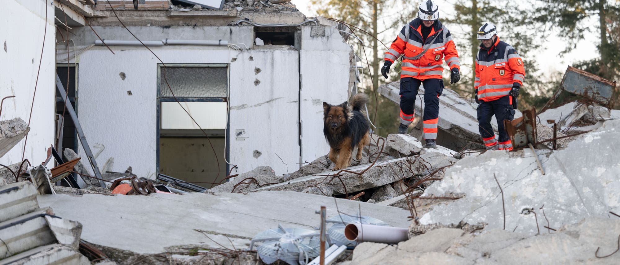 Ein Mitglied der Rettungshundestaffel läuft mit einem Hund über Trümmer