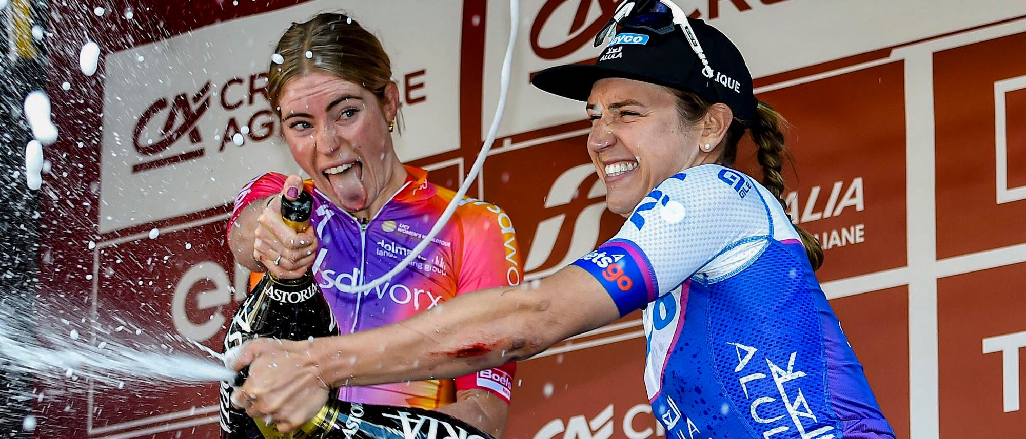 Die Siegerin Demi Vollering aus den Niederlanden und die Drittplatzierte Kristen Faulkner aus den USA feiern mit einer Champagnerdusche ihre Erfolge beim Eintagesrennen Strade Bianche 2023