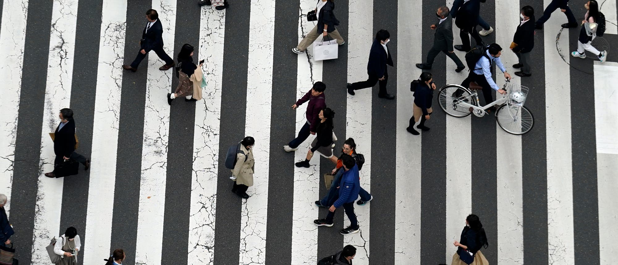 Menschen überqueren eine Straße in einem Einkaufsviertel in Tokio.