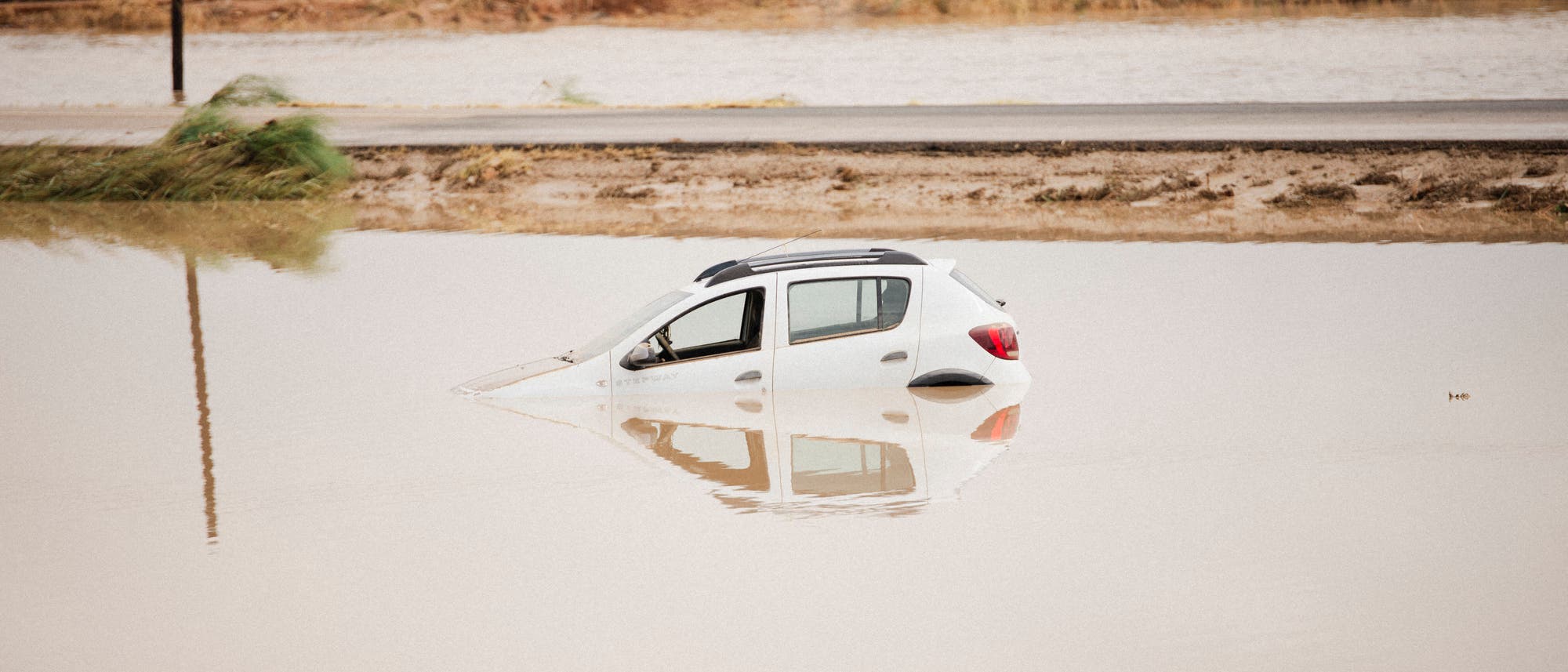 Ein Auto treibt nach heftigem Regen in einem überschwemmten Straßenstück