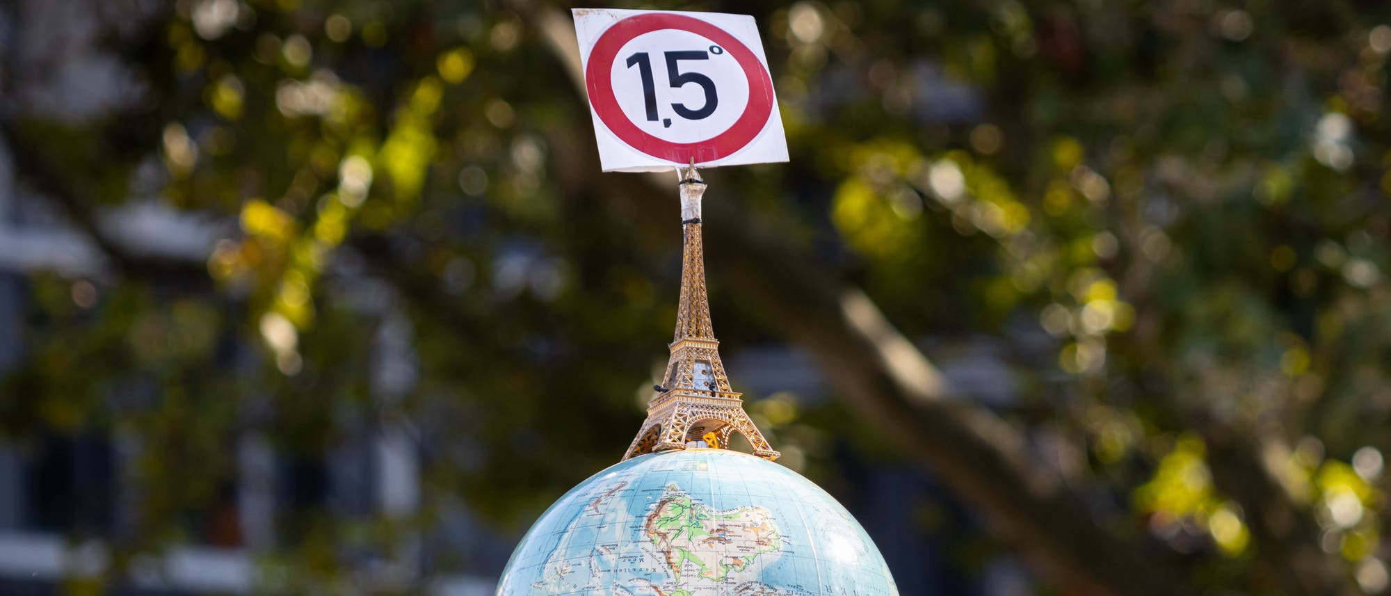 Eine Weltkugel mit Eiffelturm und 1,5-Grad-Schild