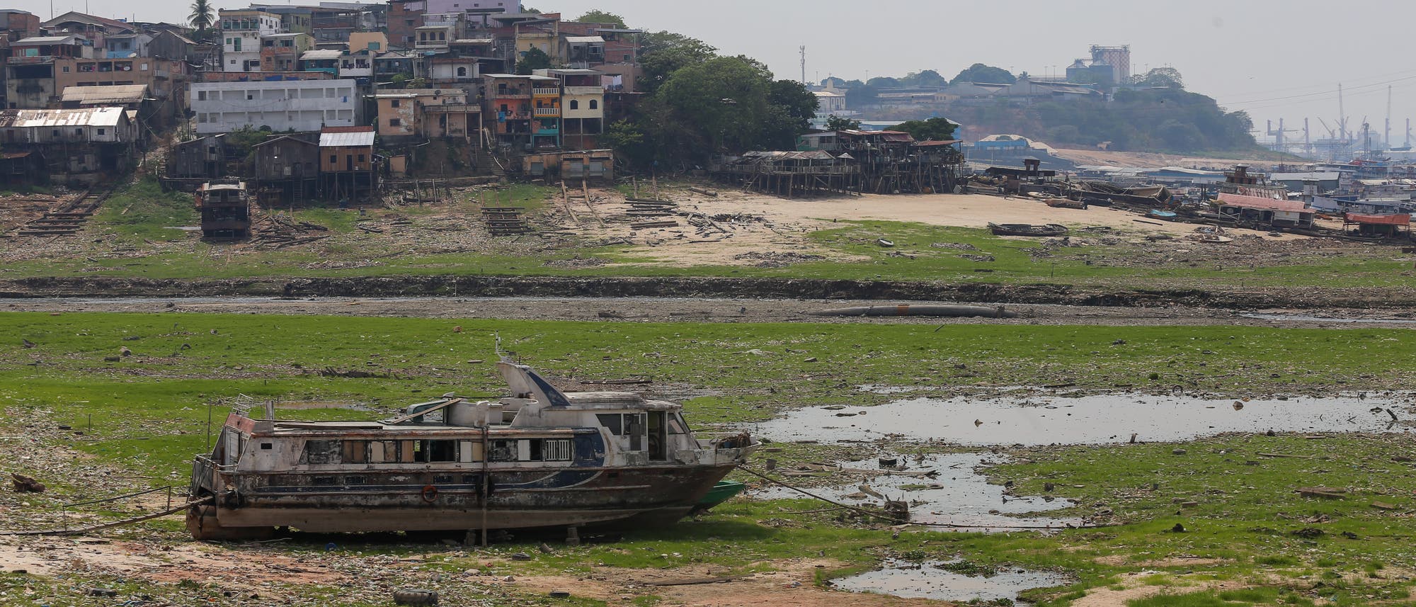 Ein Schiff liegt im trockengefallenen Hafenbecken, im Hintergrund Gebäude.