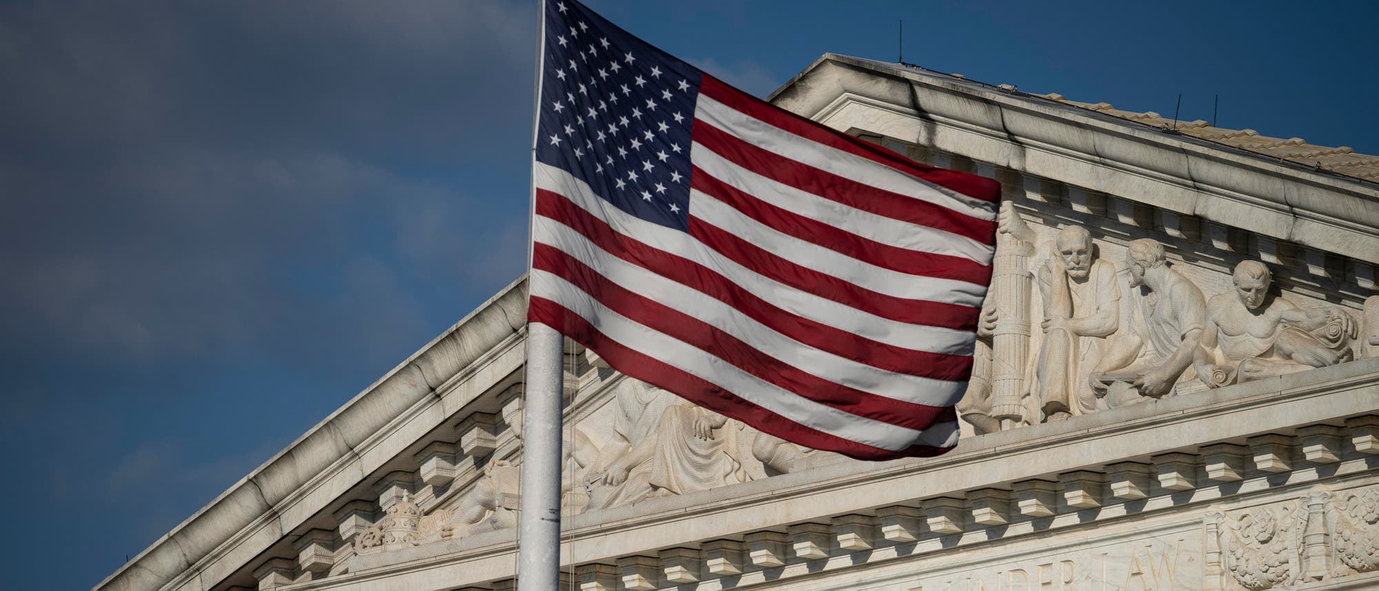 Die amerikanische Flagge weht vor einem blauen Himmel an einem Fahnenmast vor dem Supreme Court