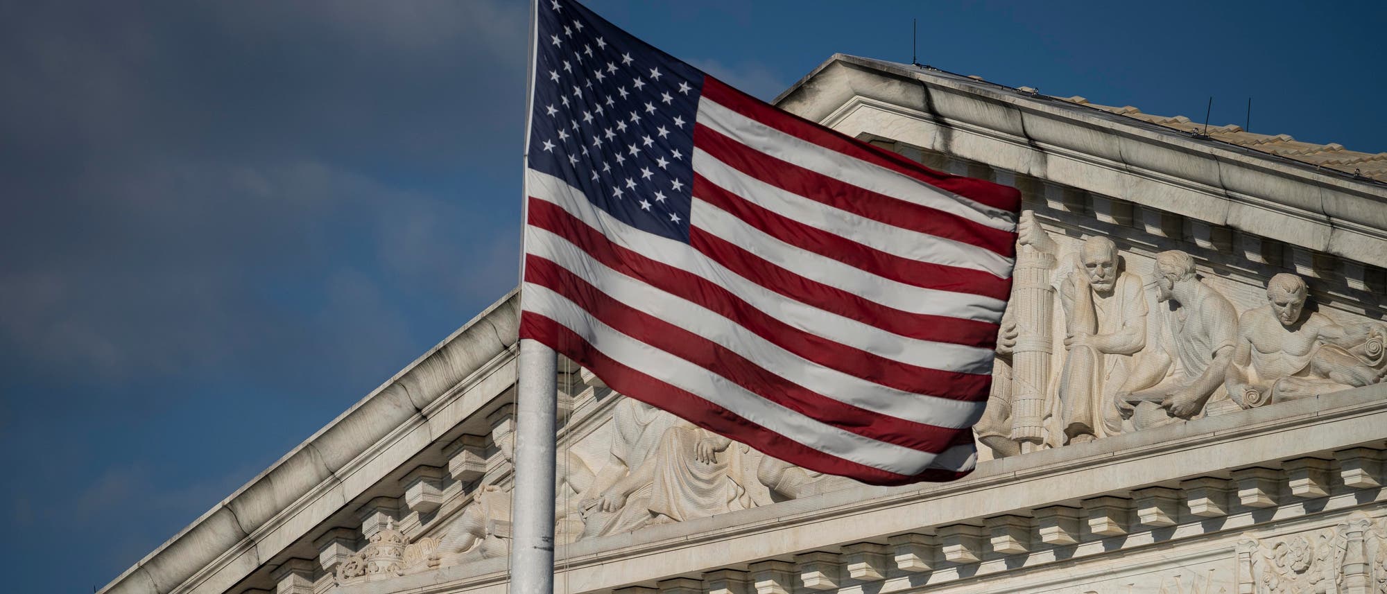 Die amerikanische Flagge weht vor einem blauen Himmel an einem Fahnenmast vor dem Supreme Court