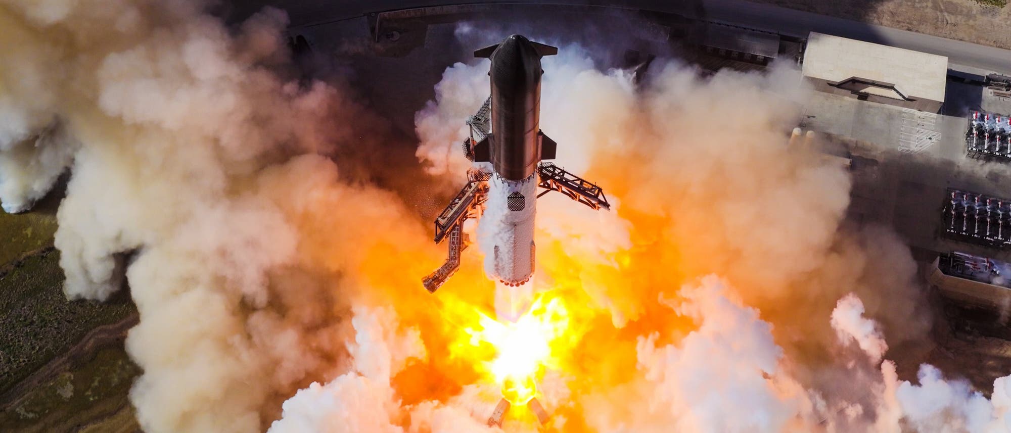 Eine Rakete hebt von einer Startrampe ab, umgeben von dichten Rauchwolken und leuchtenden Flammen. Die Szene zeigt den Moment des Starts aus der Vogelperspektive, mit der Rakete, die sich in den Himmel erhebt. Im Hintergrund sind Teile der Startrampe und die umliegende Landschaft zu sehen. Eine Rakete hebt von einer Startrampe ab, umgeben von dichten Rauchwolken und leuchtenden Flammen. Die Szene zeigt den Moment des Starts aus der Vogelperspektive, mit der Rakete, die sich in den Himmel erhebt. Im Hintergrund sind Teile der Startrampe und die umliegende Landschaft zu sehen.