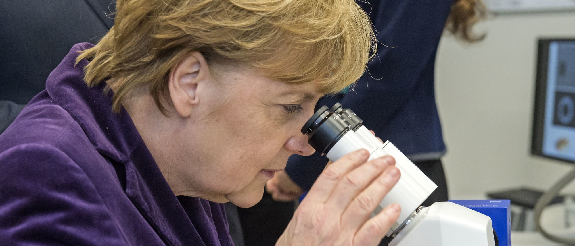 Bundeskanzlerin Angela Merkel blickt durch ein Mikroskop
