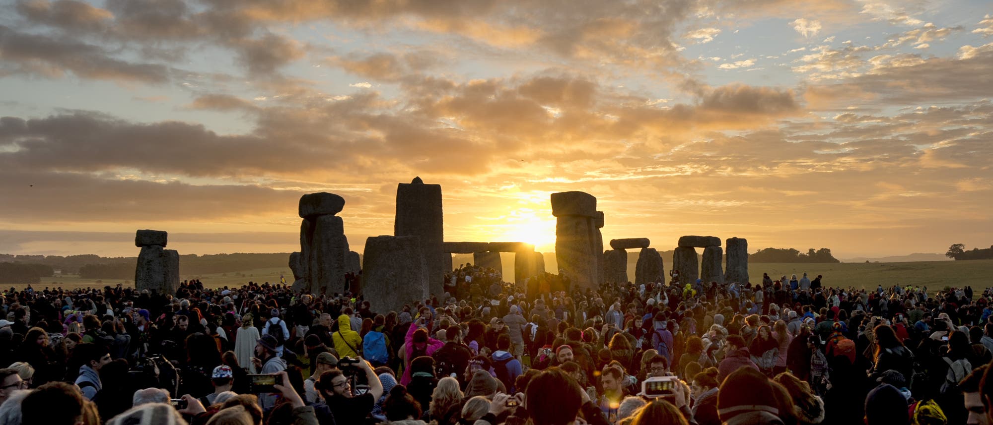 Tausende Menschen haben sich um das Stonehenge-Monument versammelt und machen Bilder vom Sonnenaufgang