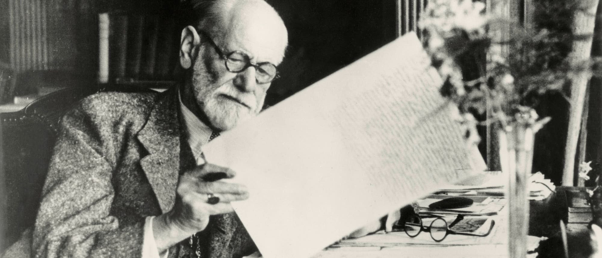 Freud liest einen Briefbogen mit Stift in der Hand