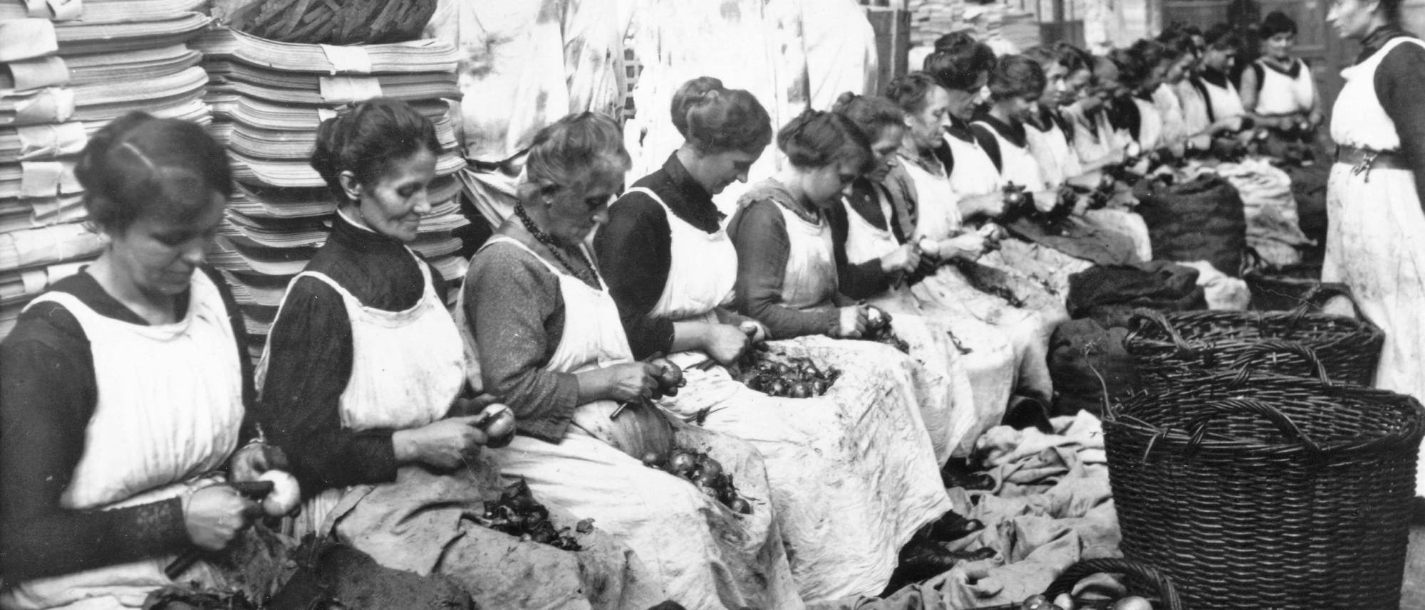 Frauen, die in einer Konservenfabrik arbeiten, schälen massenhaft Zwiebeln. Das Bild entstand während des Ersten Weltkriegs.