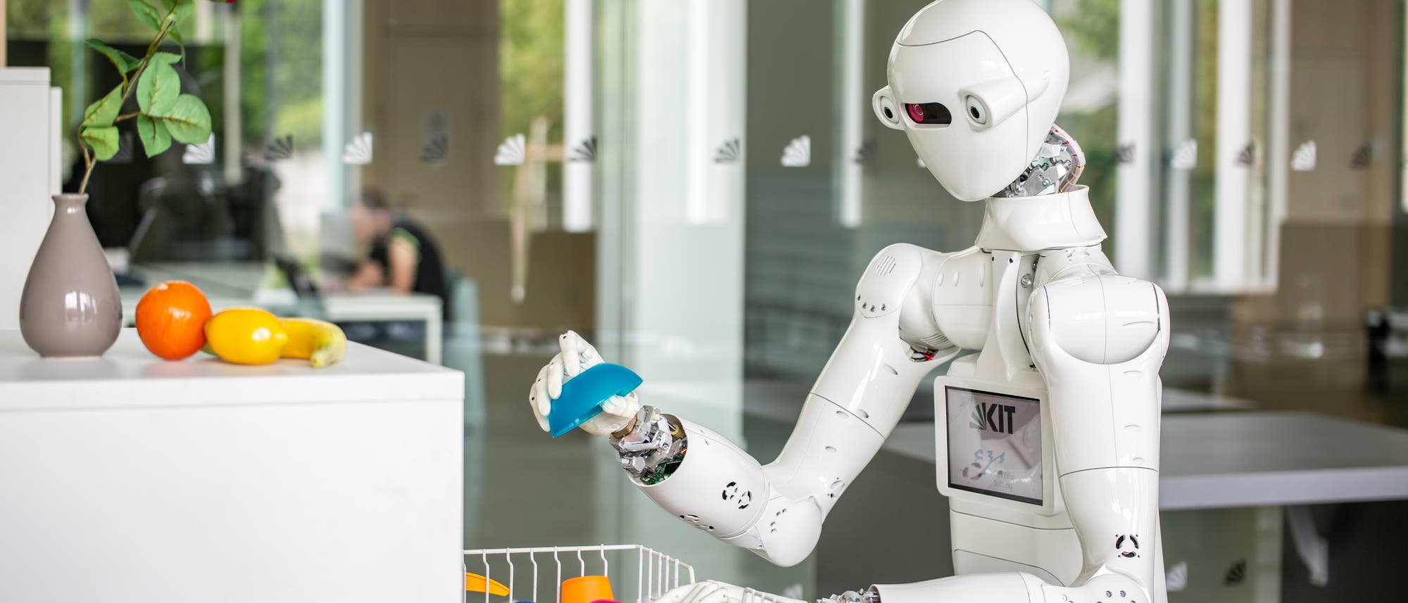 Der humanoide Roboter ARMAR-7 ist an der Sp&uuml;lmaschine besch&auml;ftigt.