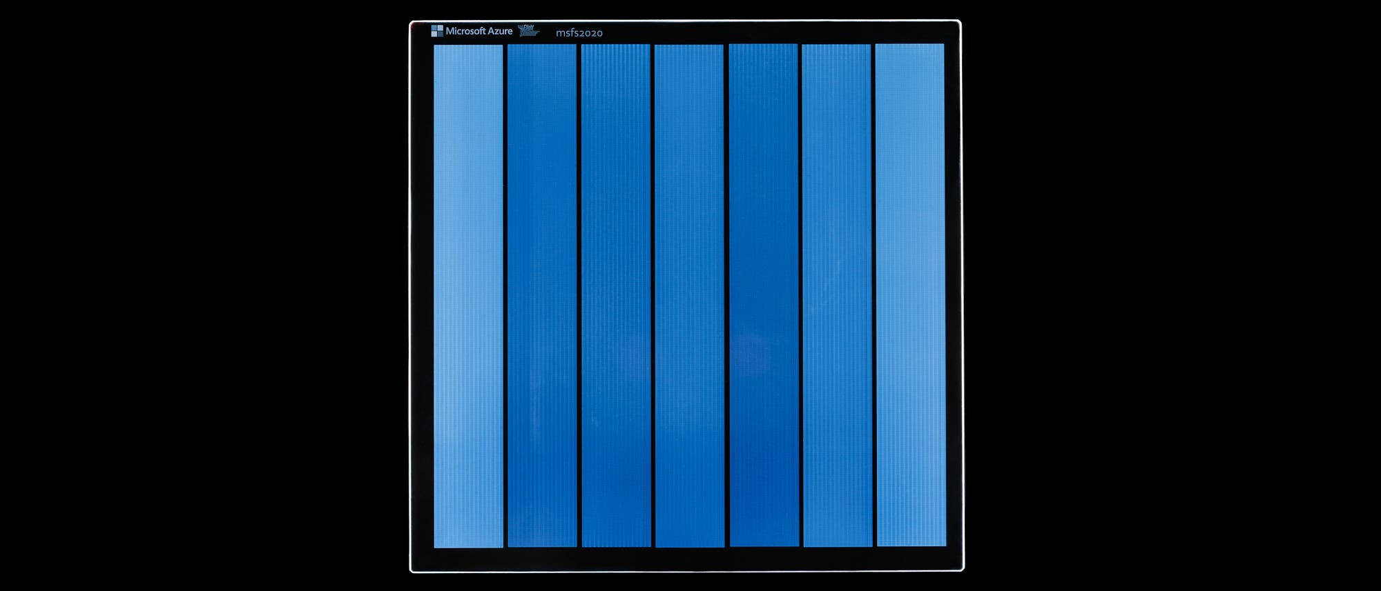 Ein Foto zeigt den Datenspeicher aus Glas von Microsoft Azure mit dem Titel "mfs2020". Die Oberfl&auml;che ist in mehrere vertikale blaue Streifen unterteilt, die gleichm&auml;&szlig;ig angeordnet sind. Der Hintergrund ist schwarz, was den Fokus auf die blauen Streifen lenkt.