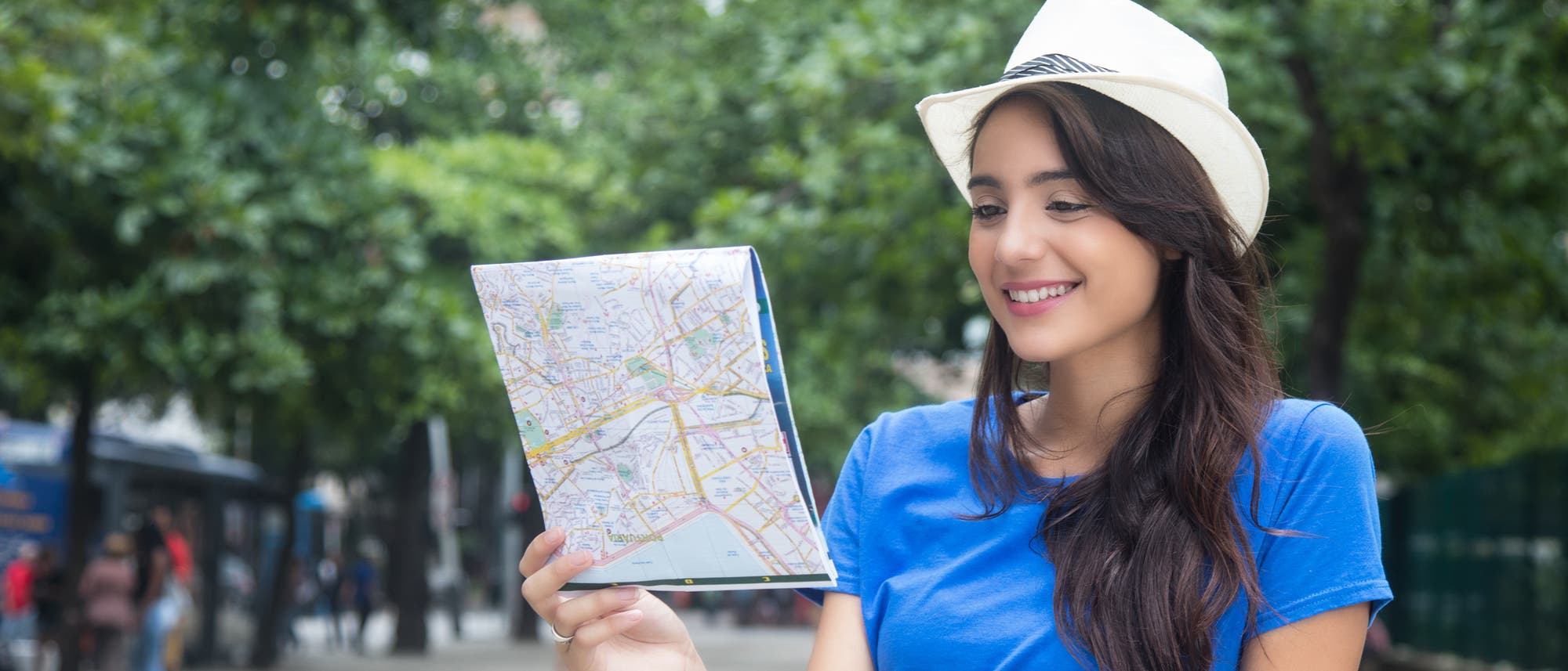 Eine junge Frau in blauem Top betrachtet einen traditionellen Stadtplan auf Papier, möglicherweise aus historischem Interesse.