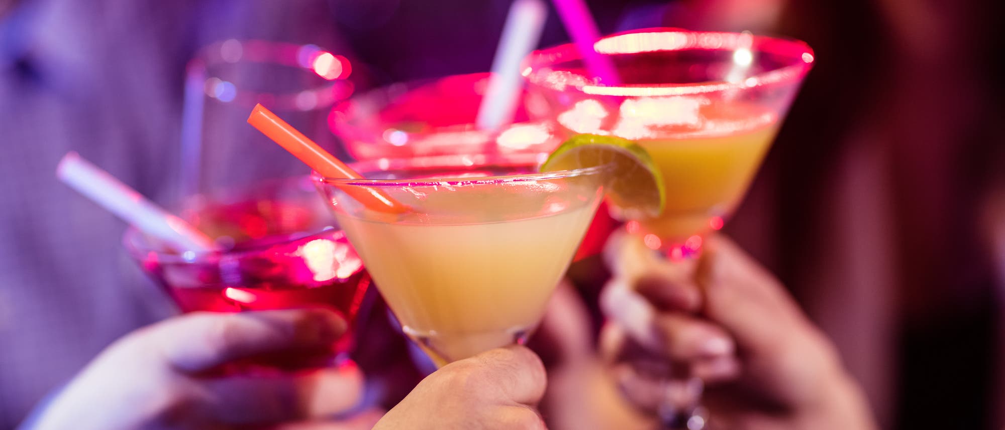 Freunde stoßen in einer Bar mit Cocktails an 