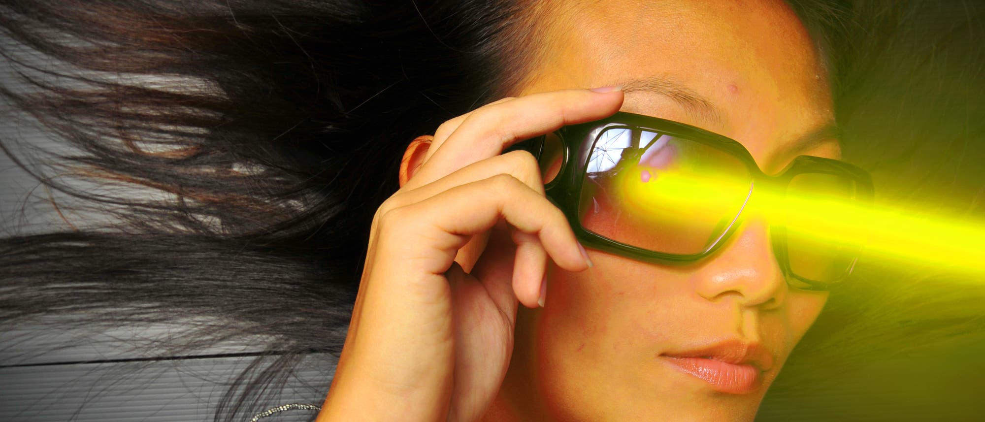 Eine junge Frau mit futuristischer Brille und ins Bild montiertem Laserstrahl.