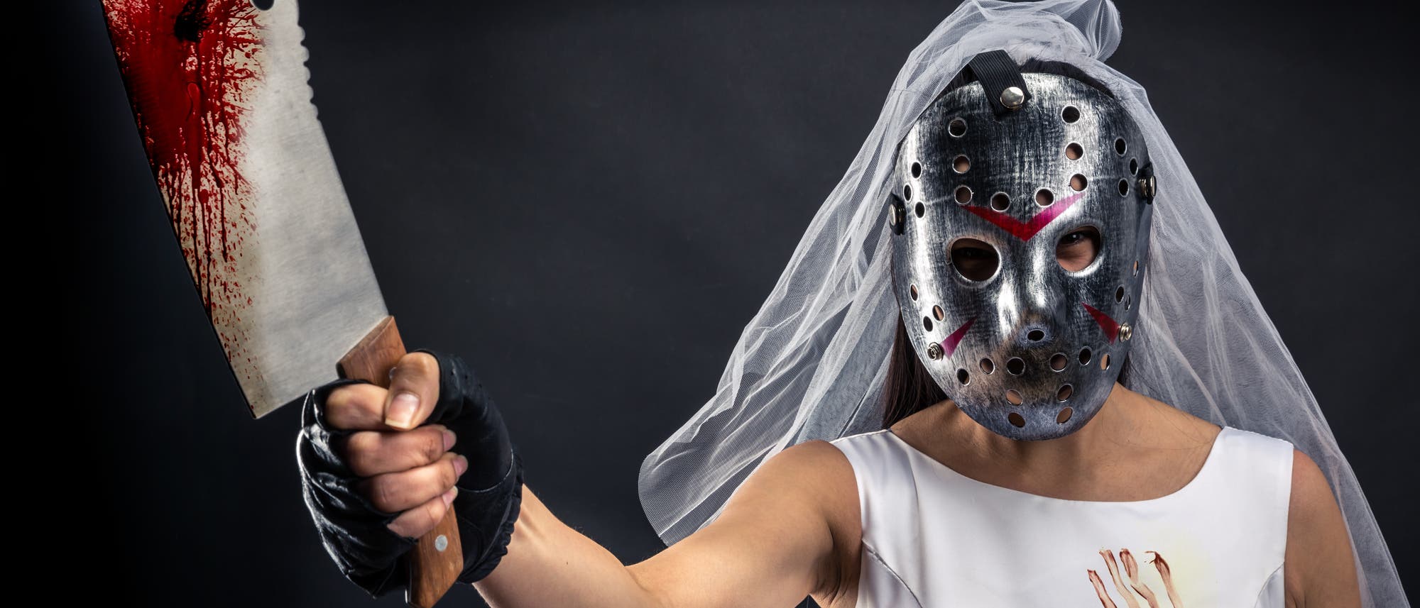 Braut mit Eishockeymaske und blutigem Hackmesser in der Hand