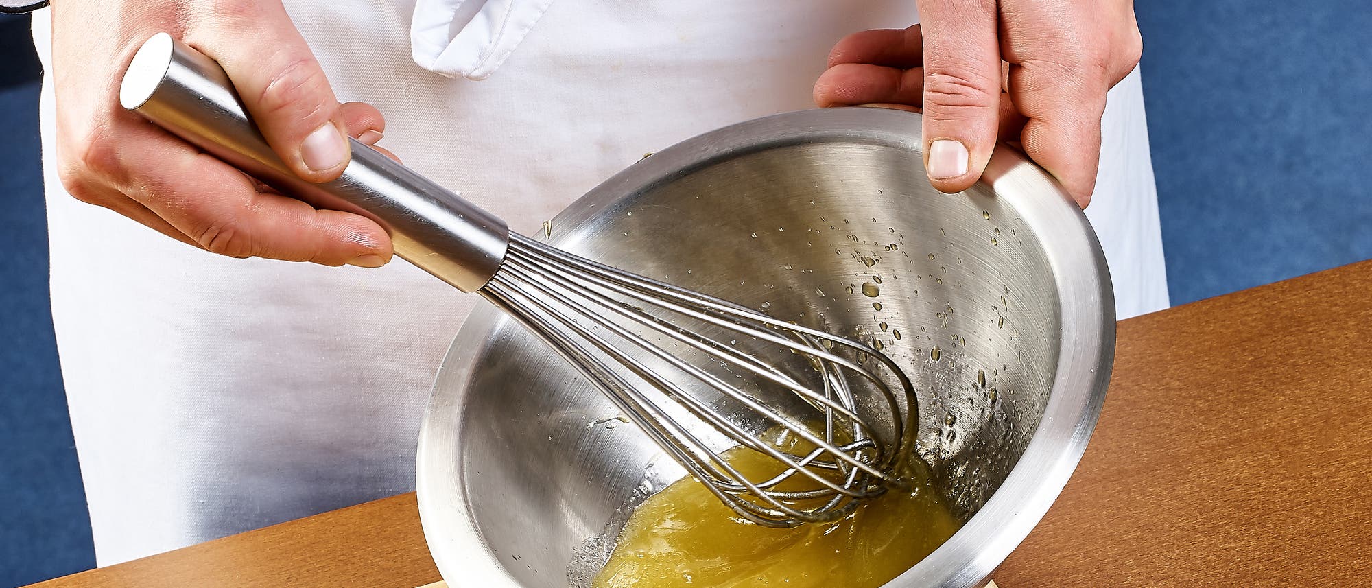 Herstellung von Mayonnaise in einer Edelstahlschüssel mit Handrührer.