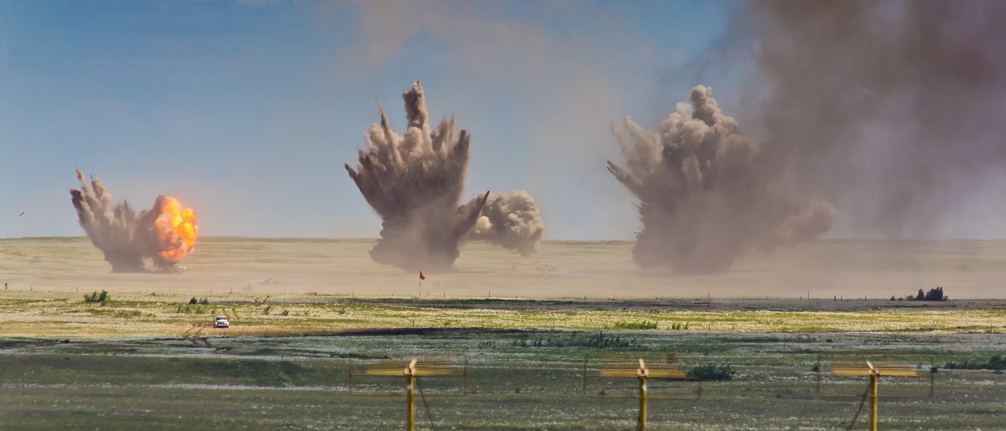 Drei Explosionen durch Fliegerbomben auf einem Truppenübungsplatz. Bei der Verbrennung von TNT entsteht viel Ruß, so dass die Rauchwolken dunkel sind.