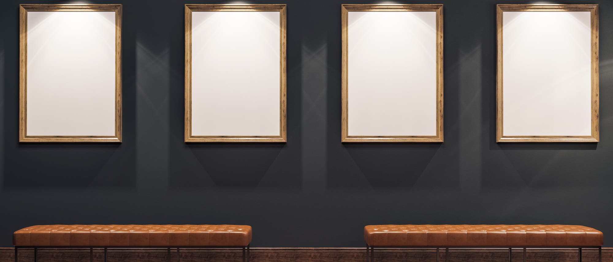 Eine Galerie mit vier leeren, beleuchteten Bilderrahmen an einer dunkelgrauen Wand. Darunter befinden sich zwei braune, gepolsterte Bänke auf einem Parkettboden. 