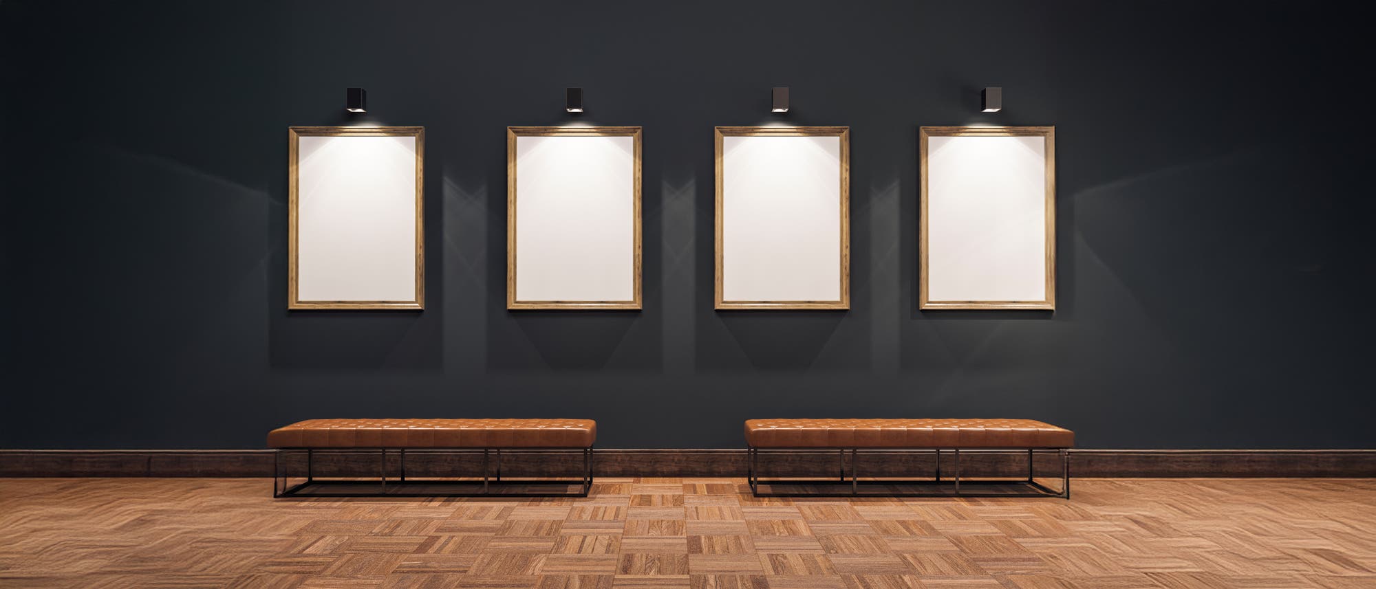 Vier leere, beleuchtete Bilderrahmen hängen an einer dunkelgrauen Wand in einer Galerie. Darunter stehen zwei braune Bänke auf einem Parkettboden. Vier leere, beleuchtete Bilderrahmen hängen an einer dunkelgrauen Wand in einer Galerie. Darunter stehen zwei braune Bänke auf einem Parkettboden.