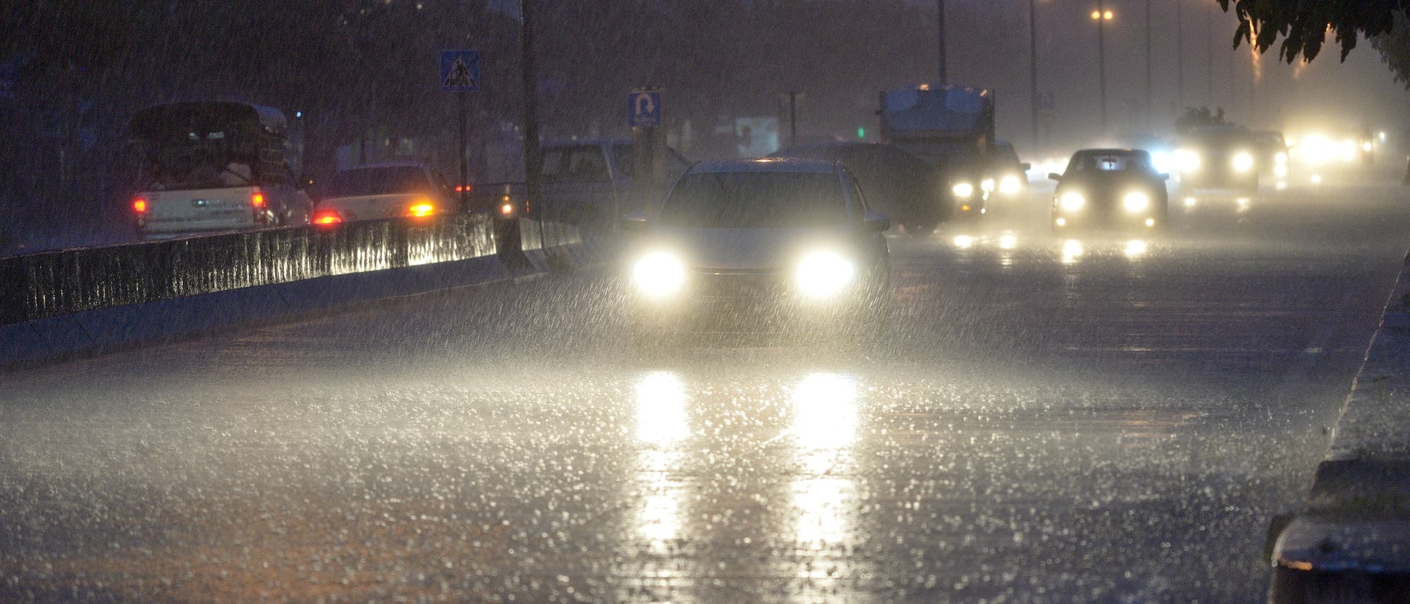 Autos auf regennasser Fahrbahn bei Nacht.