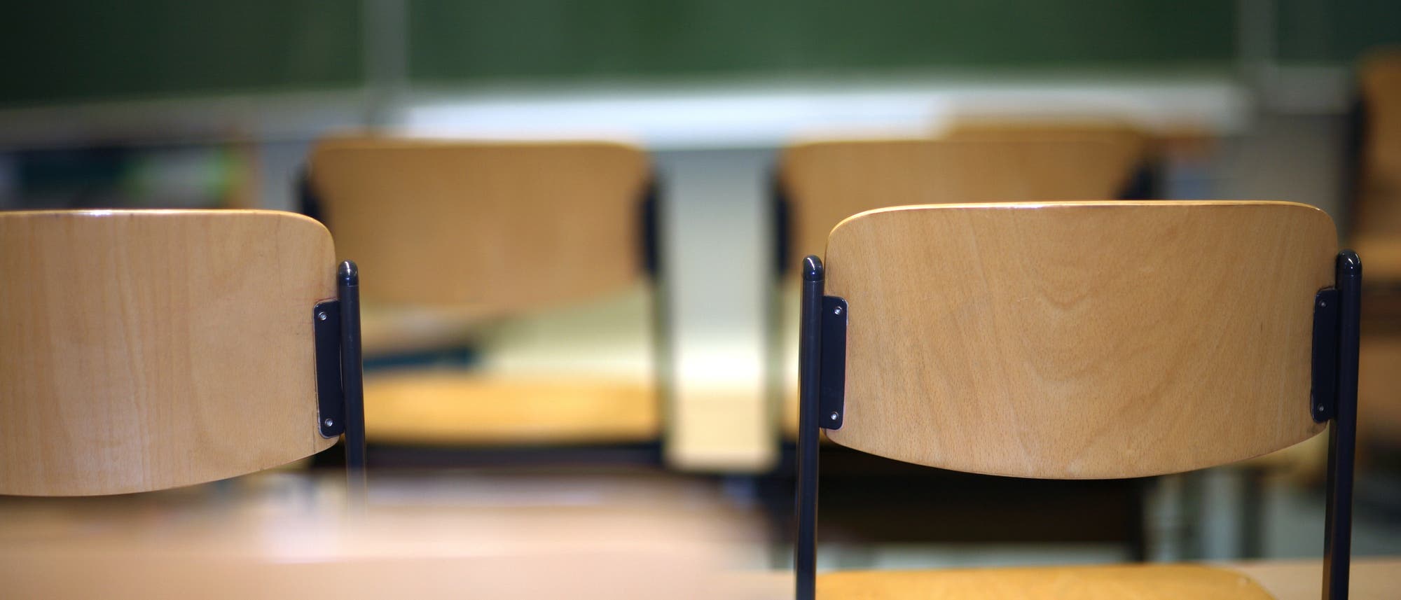 Blick auf eine Reihe von Schulstühlen Richtung Tafel