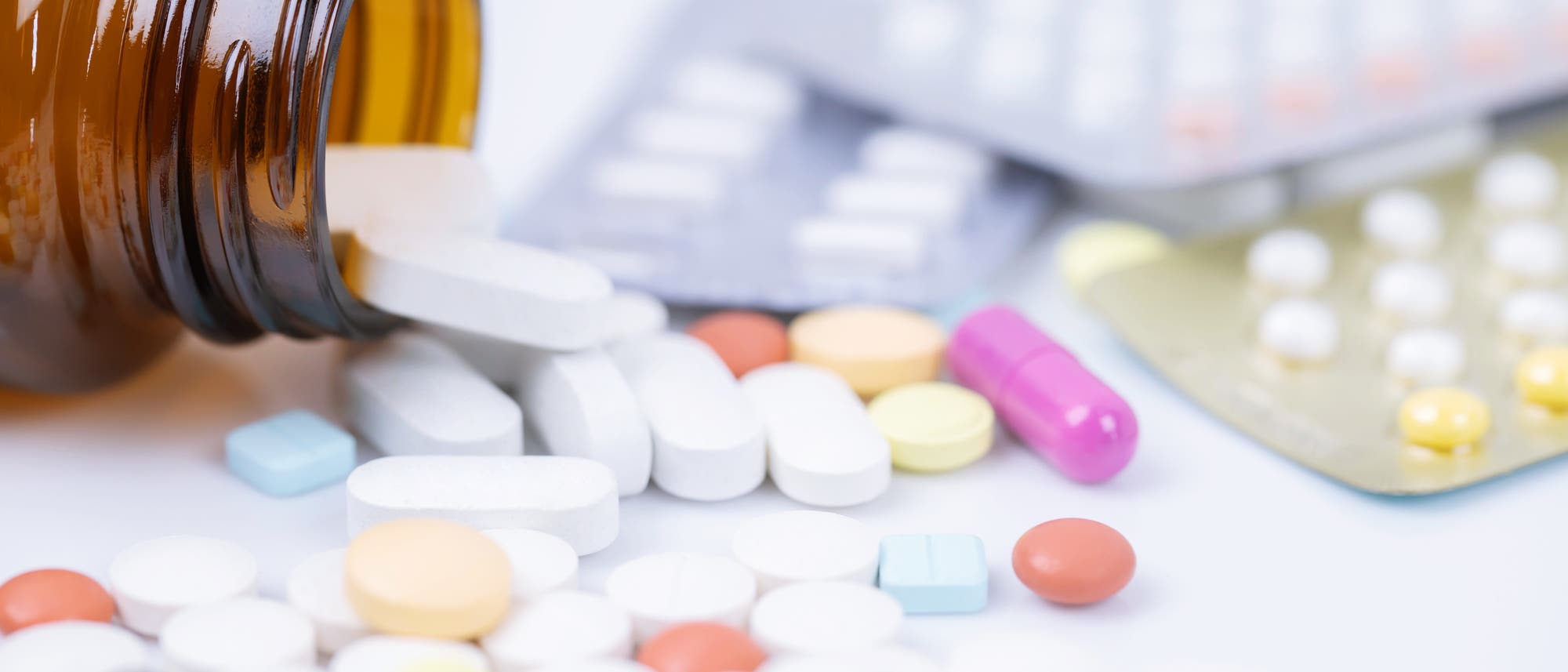Tabletten und Kapseln in verschiedenen Farben liegen durcheinander.