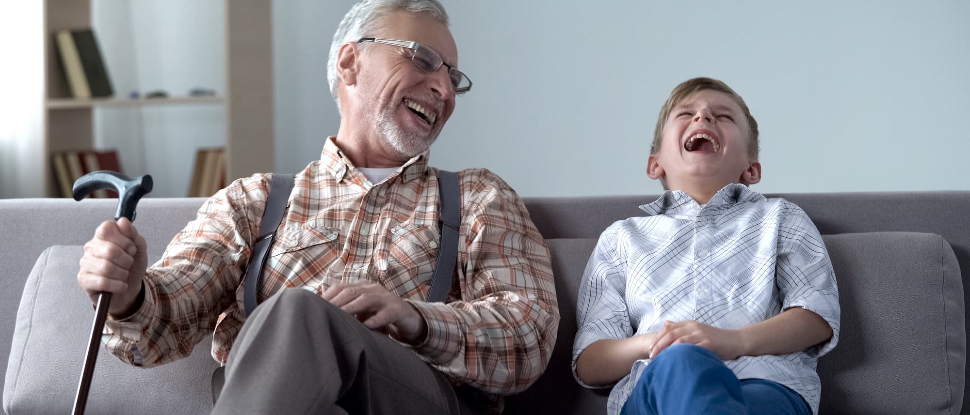 Ein alter Mann und ein Junge sitzen auf dem Sofa und lachen lauthals