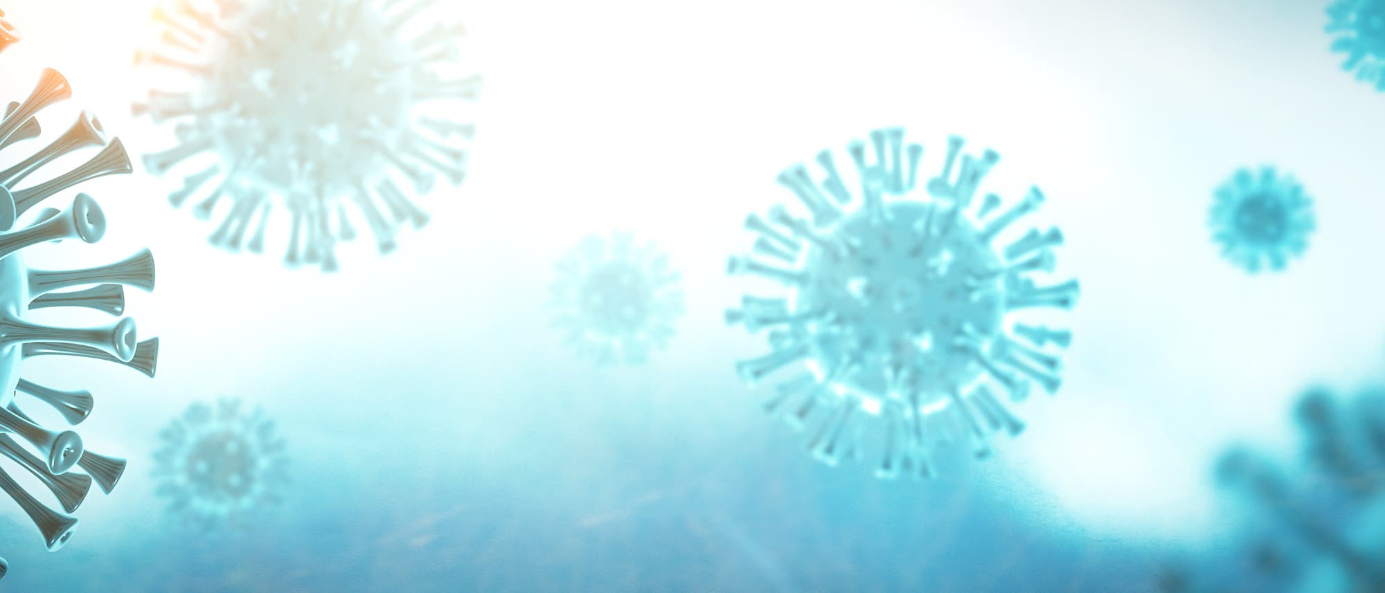 Illustration des Coronavirus Sars-CoV-2. Zu sehen sind mehrere blaue, kugelförmige Viruspartikel mit stachelartigen Strukturen auf ihrer Oberfläche, die in einer vergrößerten Ansicht gezeigt werden. Sie schweben vor einem hellen, verschwommenen Hintergrund.