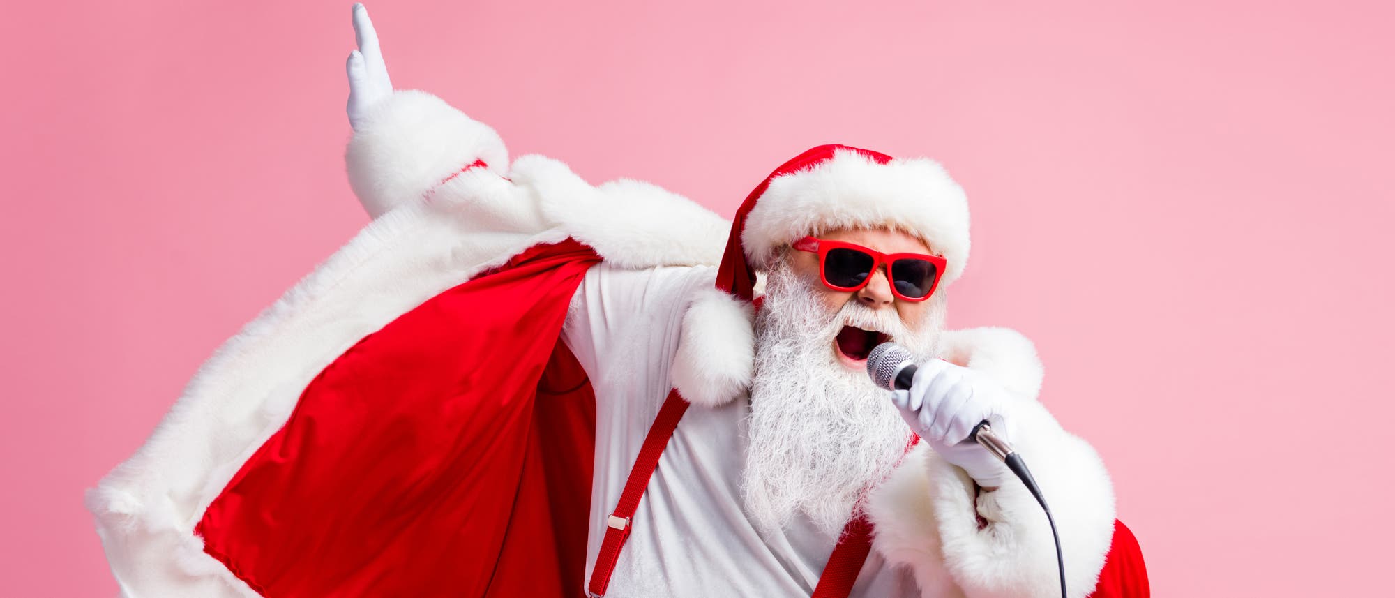 Ein Weihnachtsmann mit roter Sonnebrille und Mikrofon 