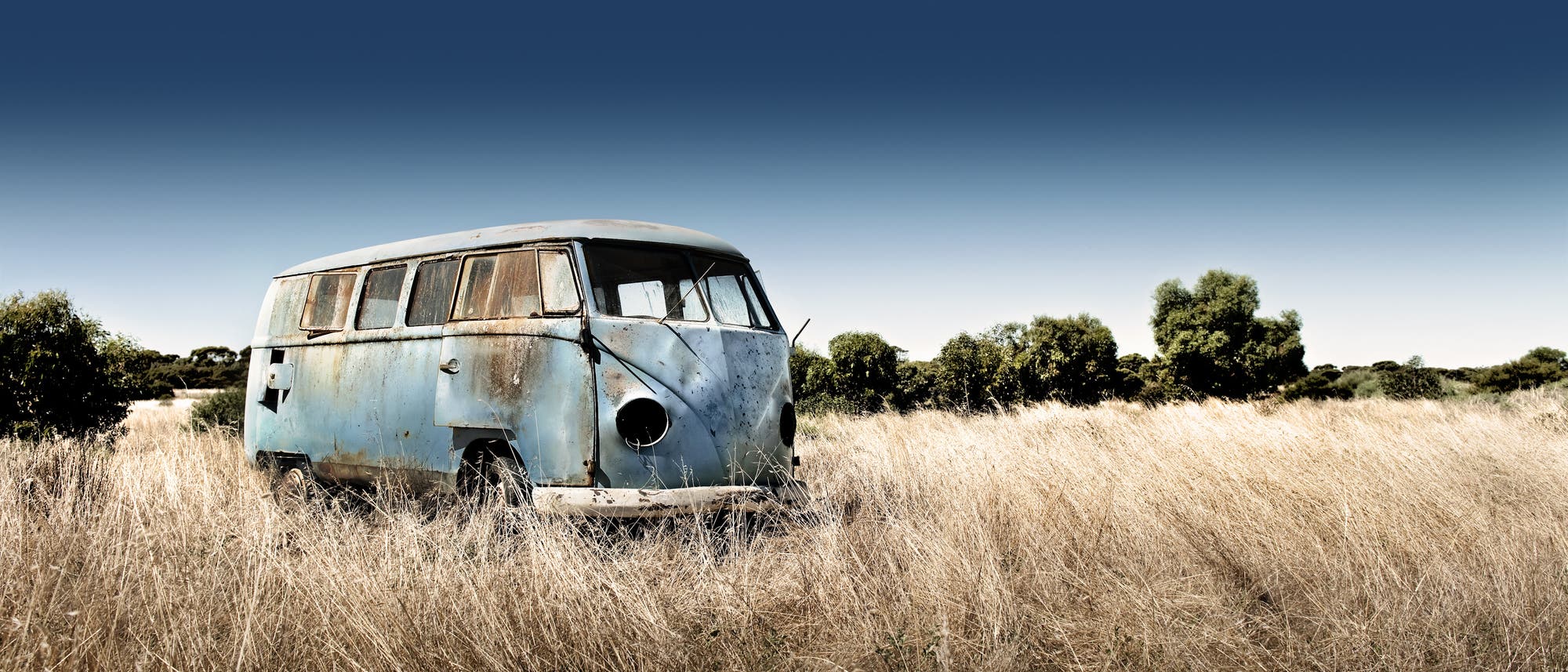 Ein verlassener Campingbus steht in der Landschaft herum.