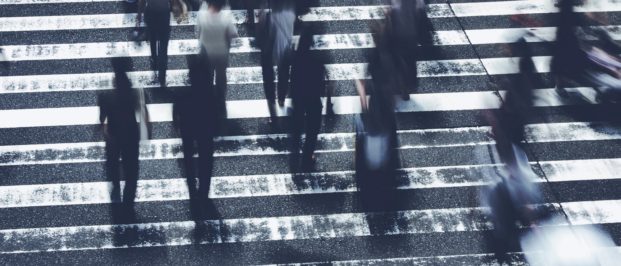 Menschen &uuml;berqueren schnellen Schrittes einen Fu&szlig;g&auml;nger&uuml;berweg auf dem Weg zur Arbeit