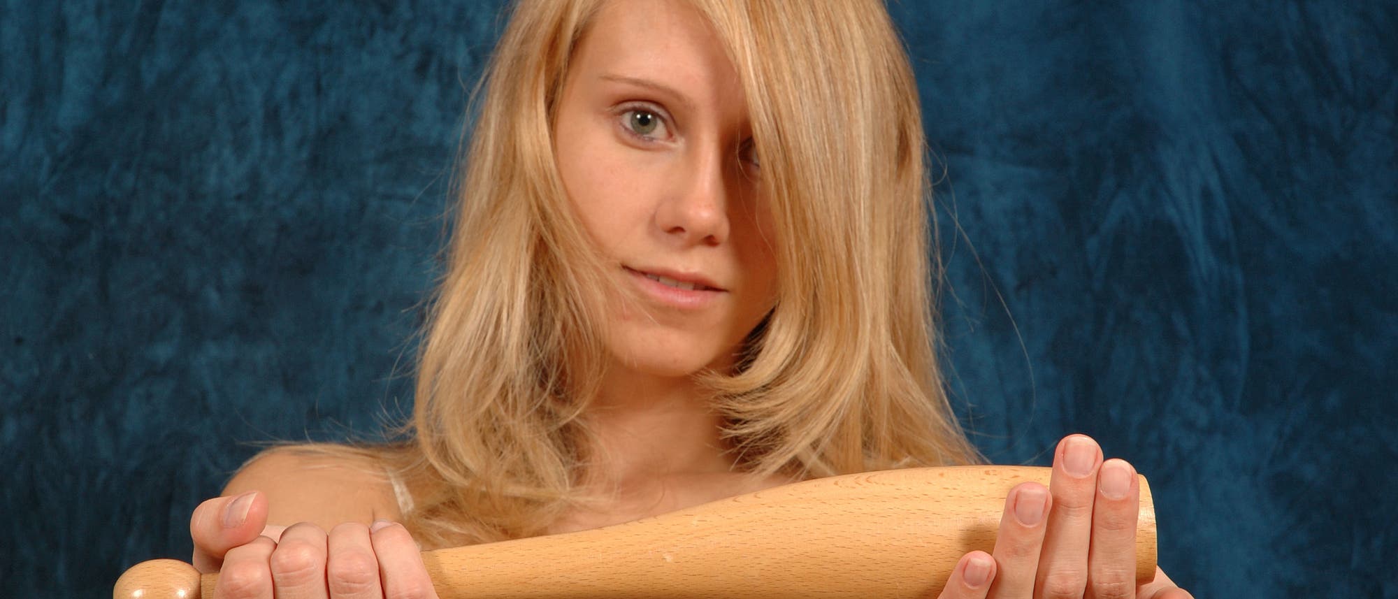 Eine blonde Frau hält eine kurze Gymnastikkeule in die Kamera.