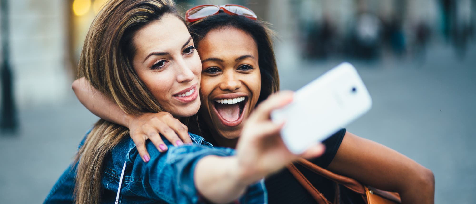 Zwei junge Frauen machen ein Selfie an einem öffentlichen Ort.