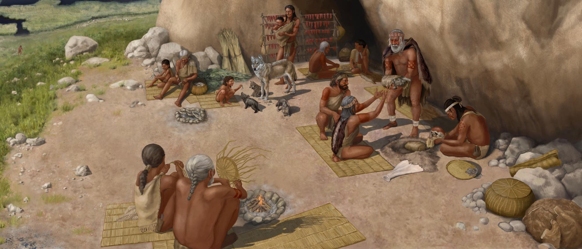 Eine k&uuml;nstlerische Darstellung einer pr&auml;historischen Gemeinschaft vor einer H&ouml;hle. Mehrere Personen sind in allt&auml;glichen Aktivit&auml;ten vertieft, darunter das Zubereiten von Nahrung und das Pflegen von Tieren. Im Vordergrund sind zwei Erwachsene, die einen Sch&auml;del betrachten, w&auml;hrend im Hintergrund getrocknetes Fleisch an einem Gestell h&auml;ngt. Ein Hund und seine Welpen sind ebenfalls zu sehen. Die Szene vermittelt ein Gef&uuml;hl von Gemeinschaft und Alltag in einer nat&uuml;rlichen Umgebung mit Blick auf eine Landschaft mit Wasser und Vegetation.