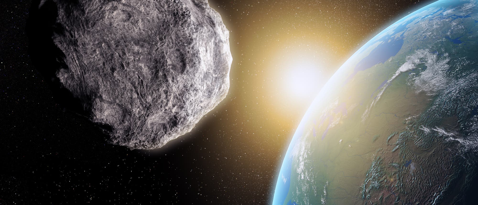 Ein Asteroid im Vordergrund fliegt auf die Erde zu. Wird er treffen? Viel spannender ist allerdings eine andere Frage: Wie kommt es eigentlich, dass die von Sonne und Erde abgewandte Seite des Asteroiden so exzellent ausgeleuchtet ist?