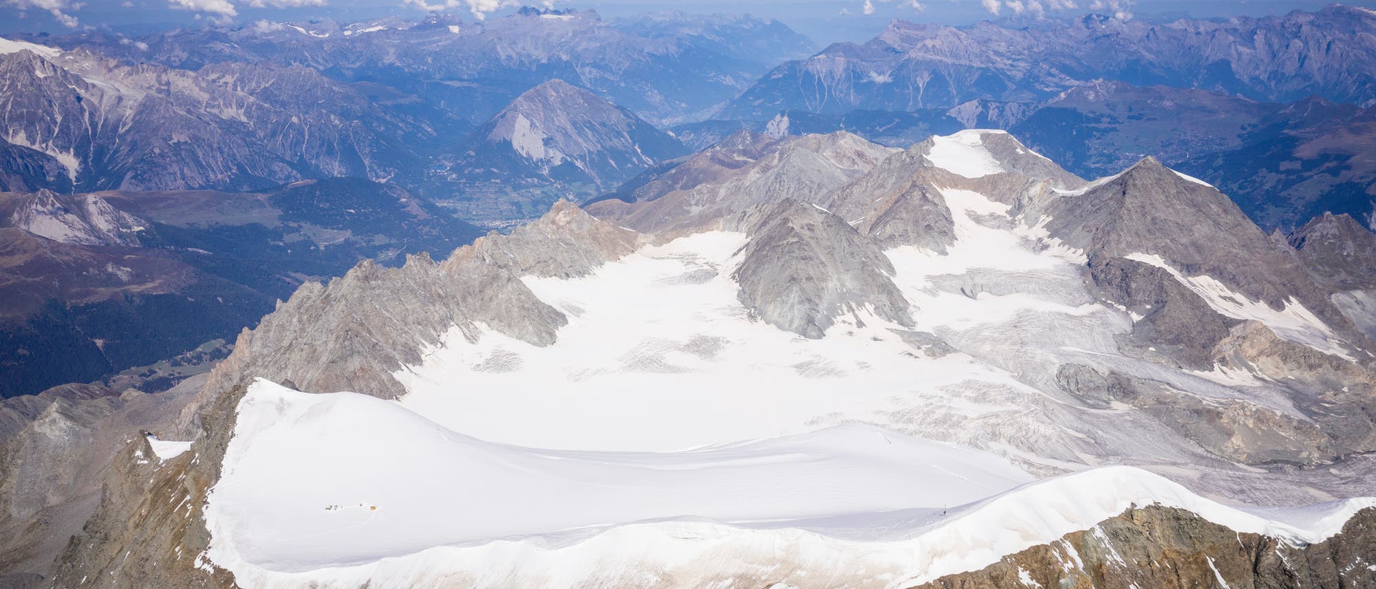 Luftaufnahme des Alpengletschers am Grand Combin: ein gletscherbedeckter Gebirgsrücken, ringsrum weitere Berggipfel ohne Schnee und Eis