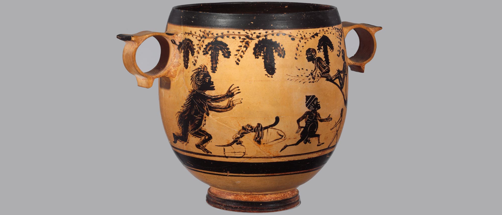 Eine antike griechische Vase mit zwei Henkeln, verziert mit schwarzen Figuren auf einem hellen Hintergrund. Die Abbildung zeigt eine Szene mit mehreren stilisierten menschlichen und tier&auml;hnlichen Figuren, die in Bewegung dargestellt sind. &Uuml;ber den Figuren sind dekorative Muster, die an Weinreben erinnern. Die Vase hat einen breiten, schwarzen Rand am oberen und unteren Ende.