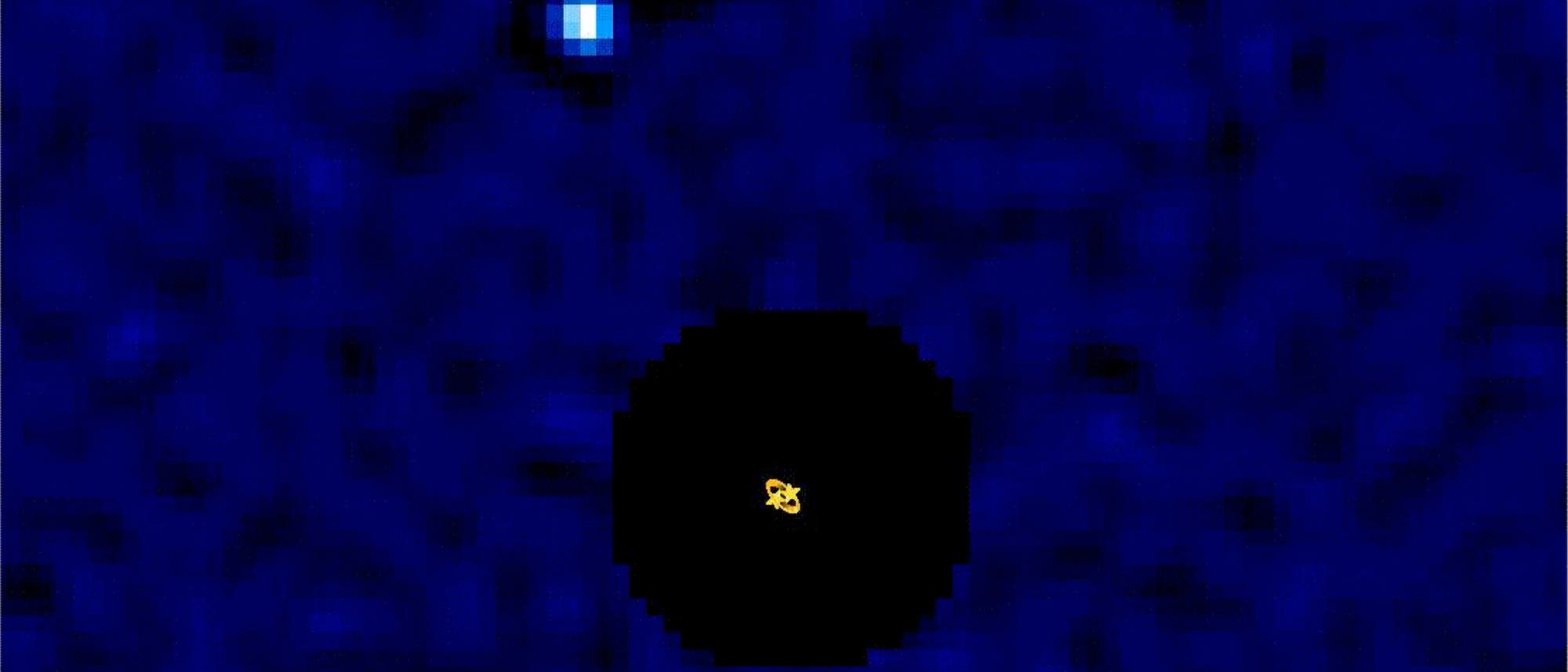 Ein astronomisches Bild zeigt einen blauen Hintergrund mit einem zentralen schwarzen Kreis, der eine helle gelbe Stelle umgibt. Oben links ist ein kleiner, leuchtender blauer Punkt zu sehen. Das Bild veranschaulicht die Position eines Himmelskörpers im Weltraum. Ein astronomisches Bild zeigt einen blauen Hintergrund mit einem zentralen schwarzen Kreis, der eine helle gelbe Stelle umgibt. Oben links ist ein kleiner, leuchtender blauer Punkt zu sehen. Das Bild veranschaulicht die Position eines Himmelskörpers im Weltraum.