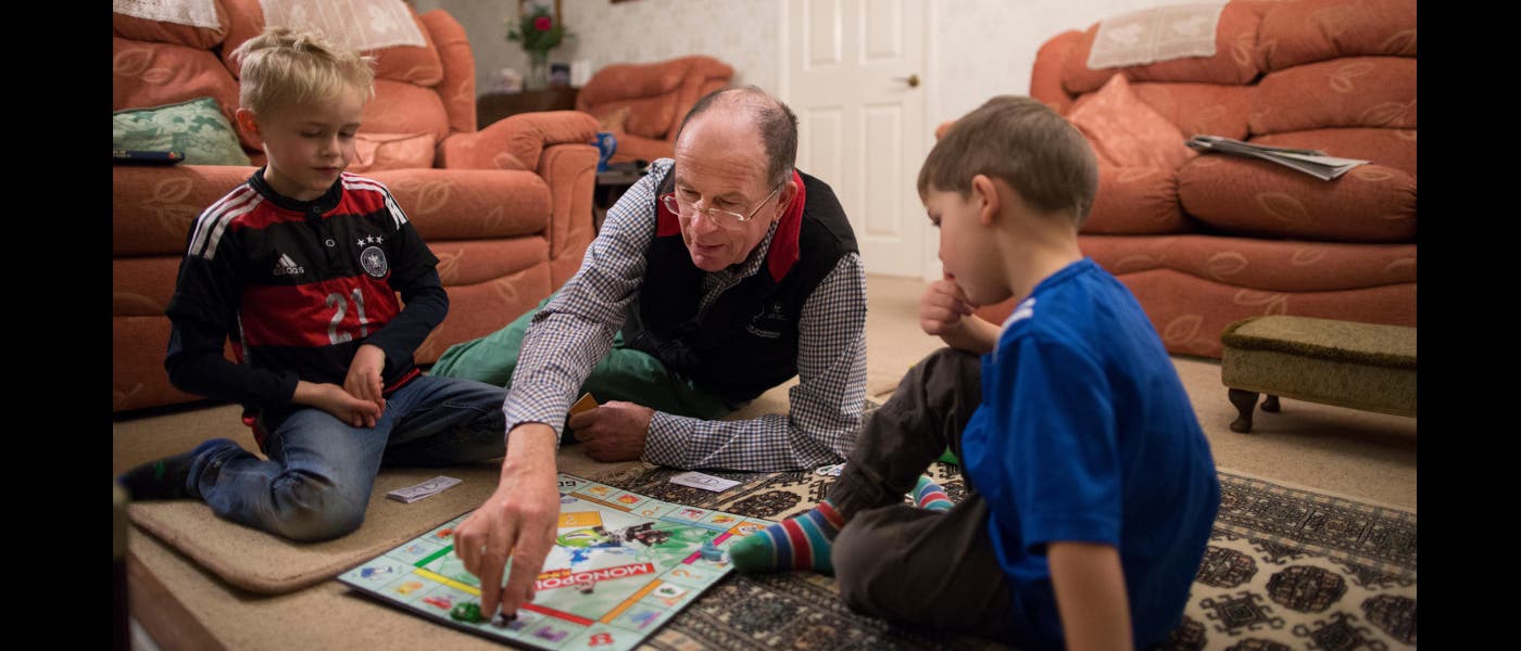 Großvater und Enkelkinder spielen Monopoly.