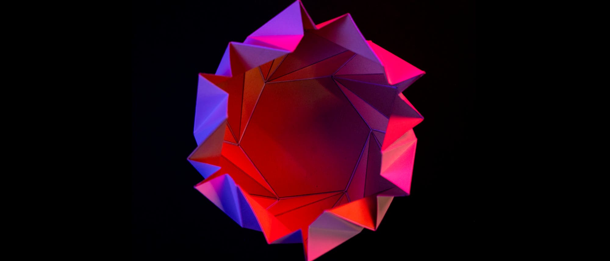 Una representación 3D de un objeto geométrico con una estructura compleja en forma de estrella. La superficie consiste en facetas triangulares, que se iluminan en diferentes tonos rojos y morados. La iluminación crea un gradiente dinámico que enfatiza la forma de tres dimensiones. El fondo es oscuro, lo que enfatiza el objeto. Una representación 3D de un objeto geométrico con una estructura compleja en forma de estrella. La superficie consiste en facetas triangulares, que se iluminan en diferentes tonos rojos y morados. La iluminación crea un gradiente dinámico que enfatiza la forma de tres dimensiones. El fondo es oscuro, lo que enfatiza el objeto.